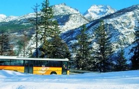 Dağlık arka plana sahip İsviçre kırsalında seyahat eden İsviçre Postbus'un fotoğrafı